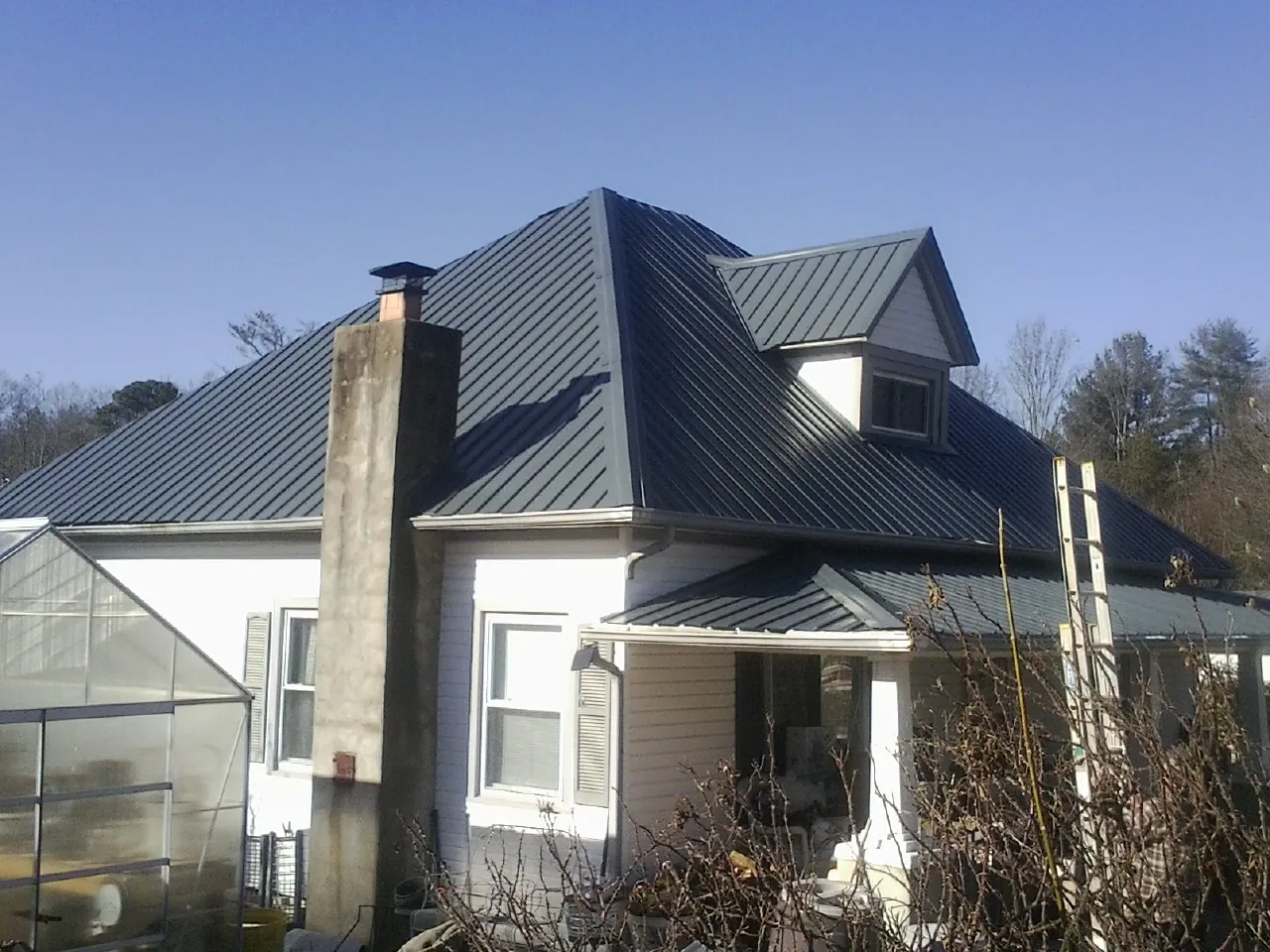 Dark blue standing seam metal roof on a white farmhouse with dormer — Slate & Tile Roof Repair by Roofing Brothers in Ansted