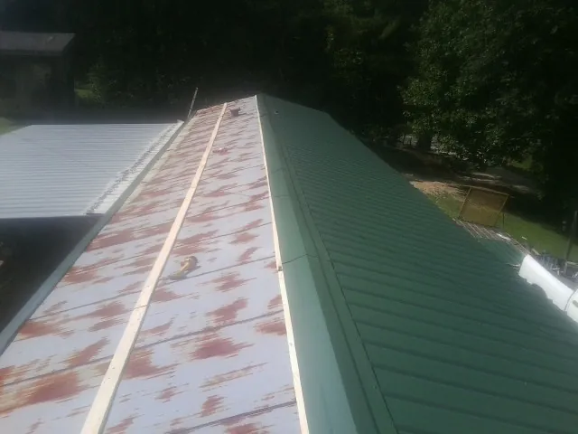 Old rusted panels beside newly installed green metal roofing — Wind Damage Roof Repair by Roofing Brothers in Ansted