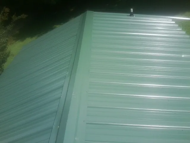 New green metal panels meeting at the ridge of a roof — Flat Roof Repair work by our crew in Ansted