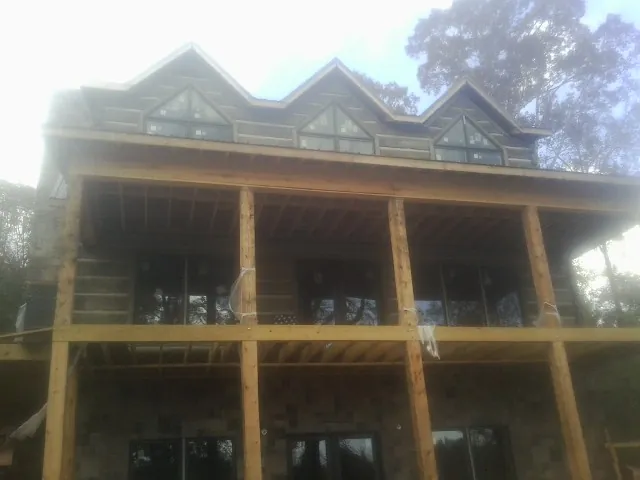 Dormers and porch framing on a large log home under construction — Roof Coating work by our crew in Ansted