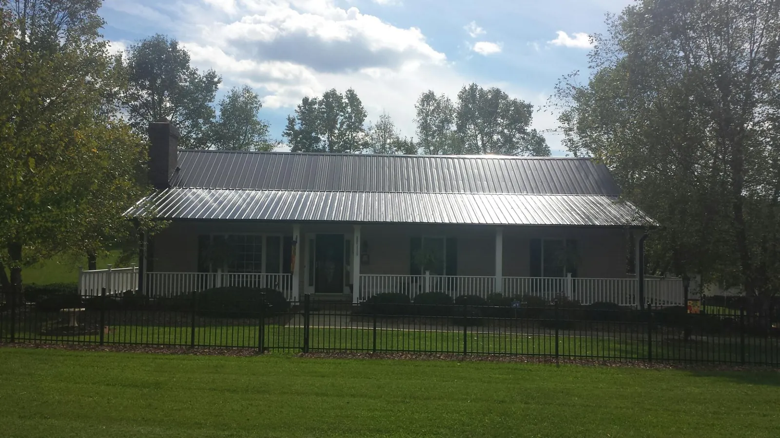 Gray metal roof on a brick ranch with a full width front porch — Gutter Guard Installation work by our crew in Ansted