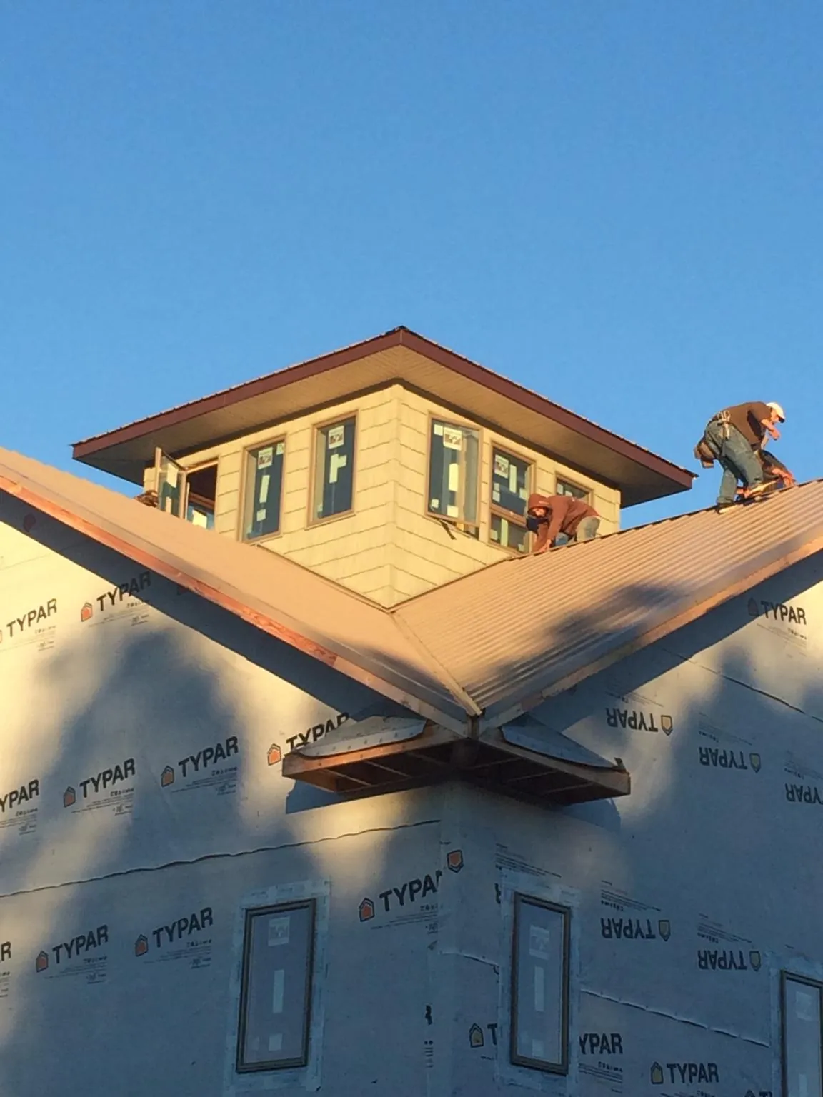 Roofers working around a rooftop cupola on a new metal roof at sunset — Roof Waterproofing in Ansted by Roofing Brothers